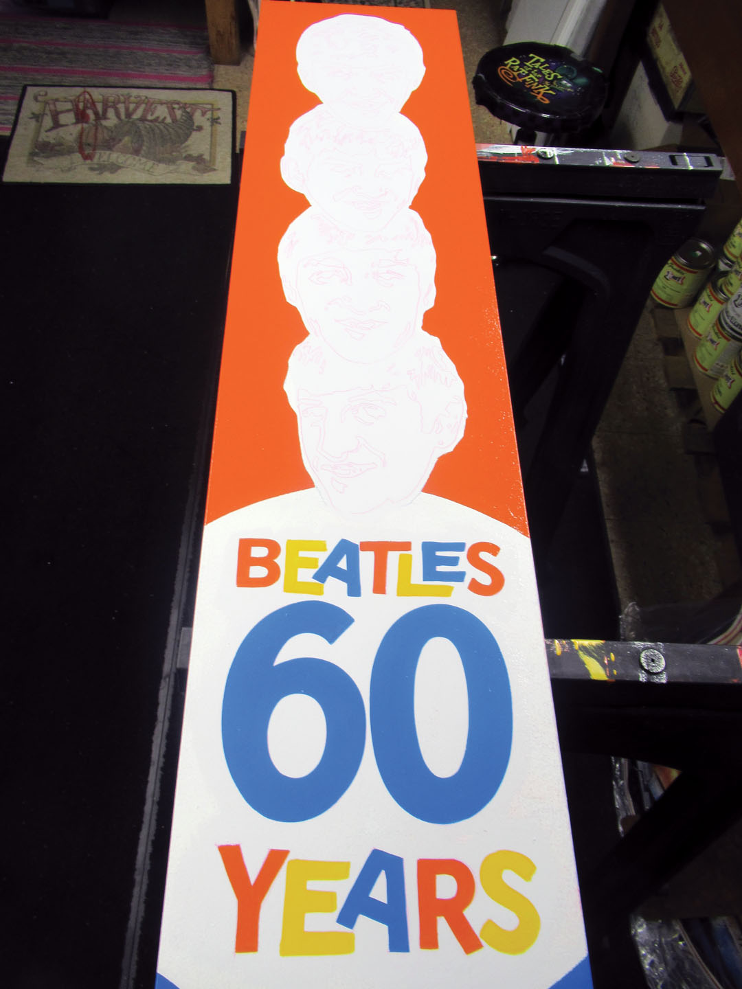In this sequence of photos, you can see how I “spotted in” the orange, blue and yellow lettering on the white panel, then “cut in” the black. The white background behind the lighter colors gives added brilliance for maximum readability. The dark background easily covers the light colors in one coat.